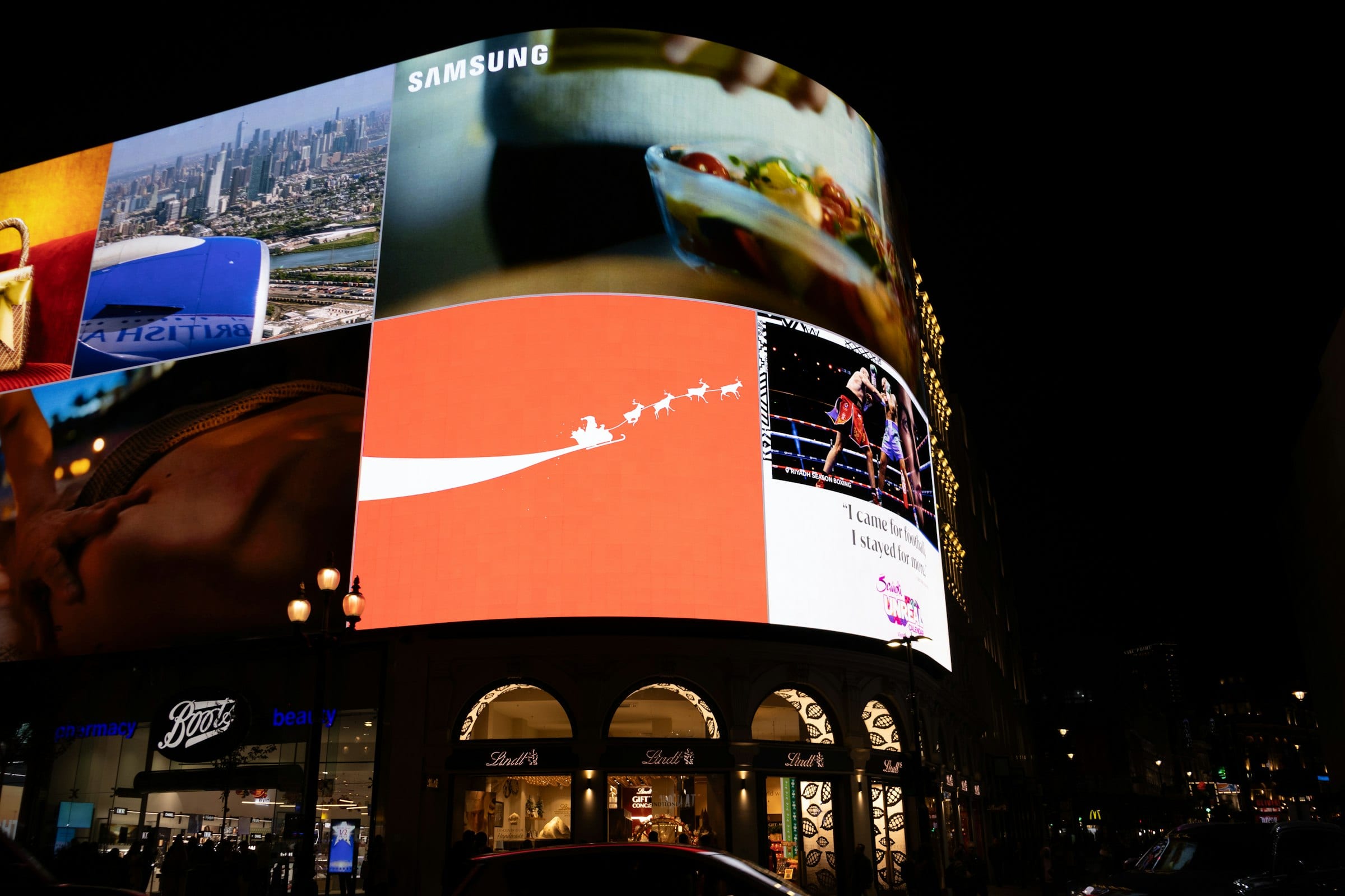 Giant digital LED advertising screens lit up against a night sky